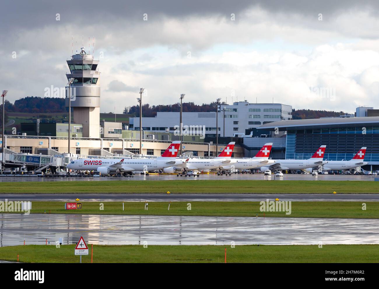 Flughafen Zürich ATC und Terminal mit Swiss Airlines Flugzeugen, die bei Regenwetter geparkt sind. Flugsicherungsturm des Flughafens Kloten in Swizterland. Stockfoto