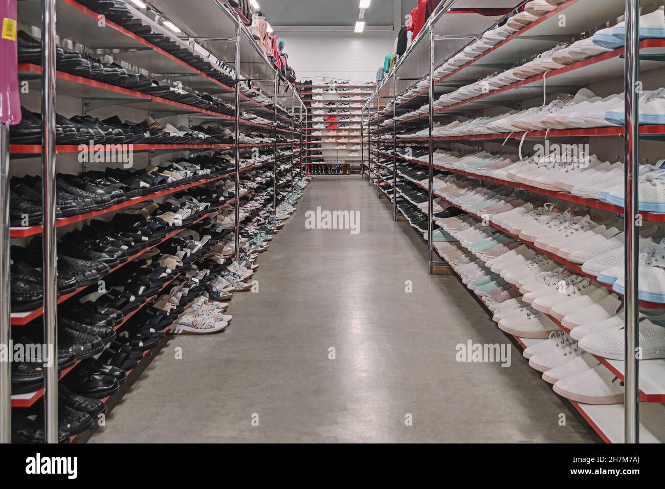 Seitenansicht des Schuhgeschäft Regale mit der Partien von sneakers zum Verkauf. Low-budget-bequeme Schuhe einkaufen. Unisex stilvolle Teenager Schuhe. Reihen von neuen Stockfoto