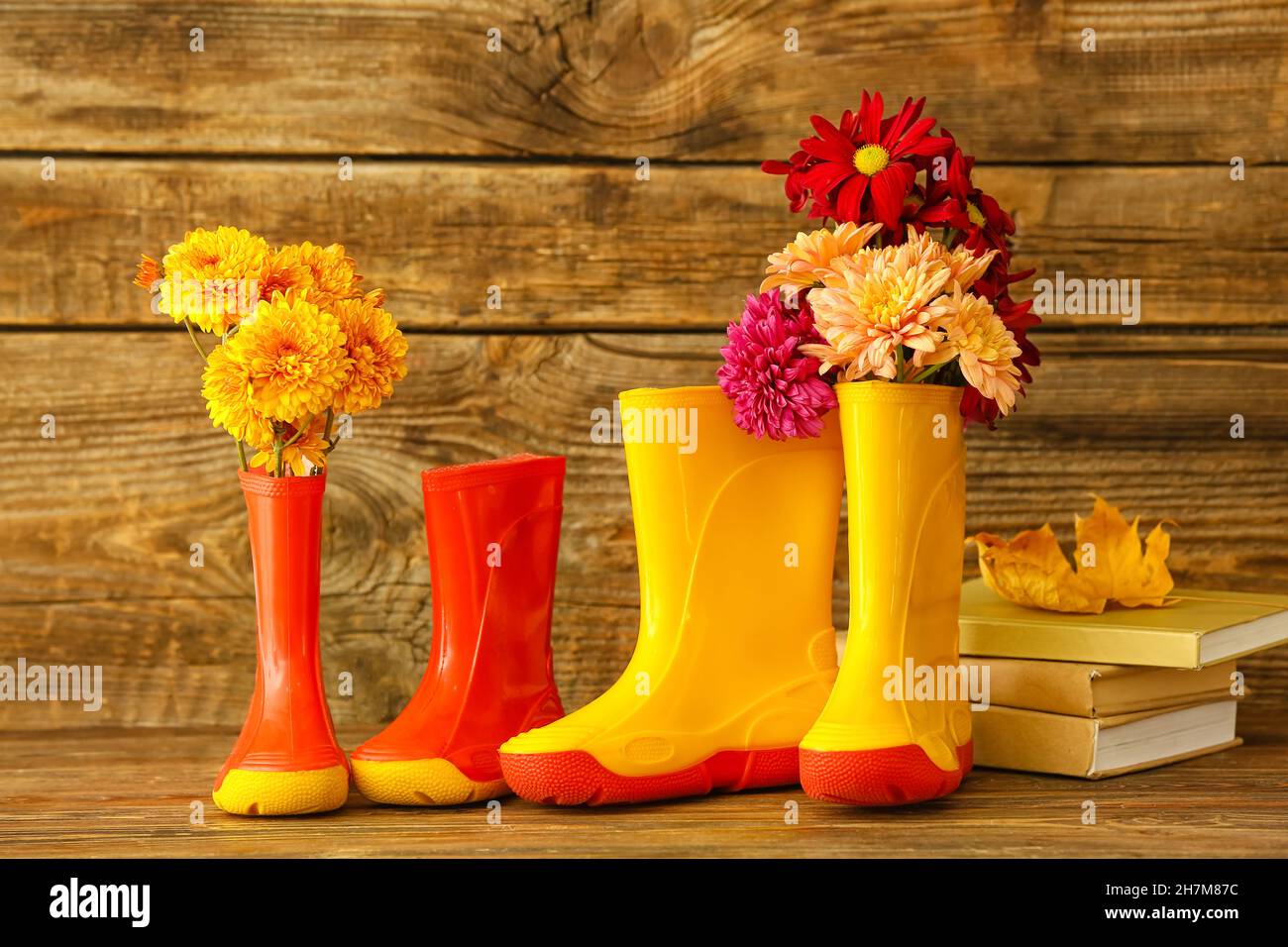 Gummistiefel, Blumen und Bücher auf Holzhintergrund Stockfoto