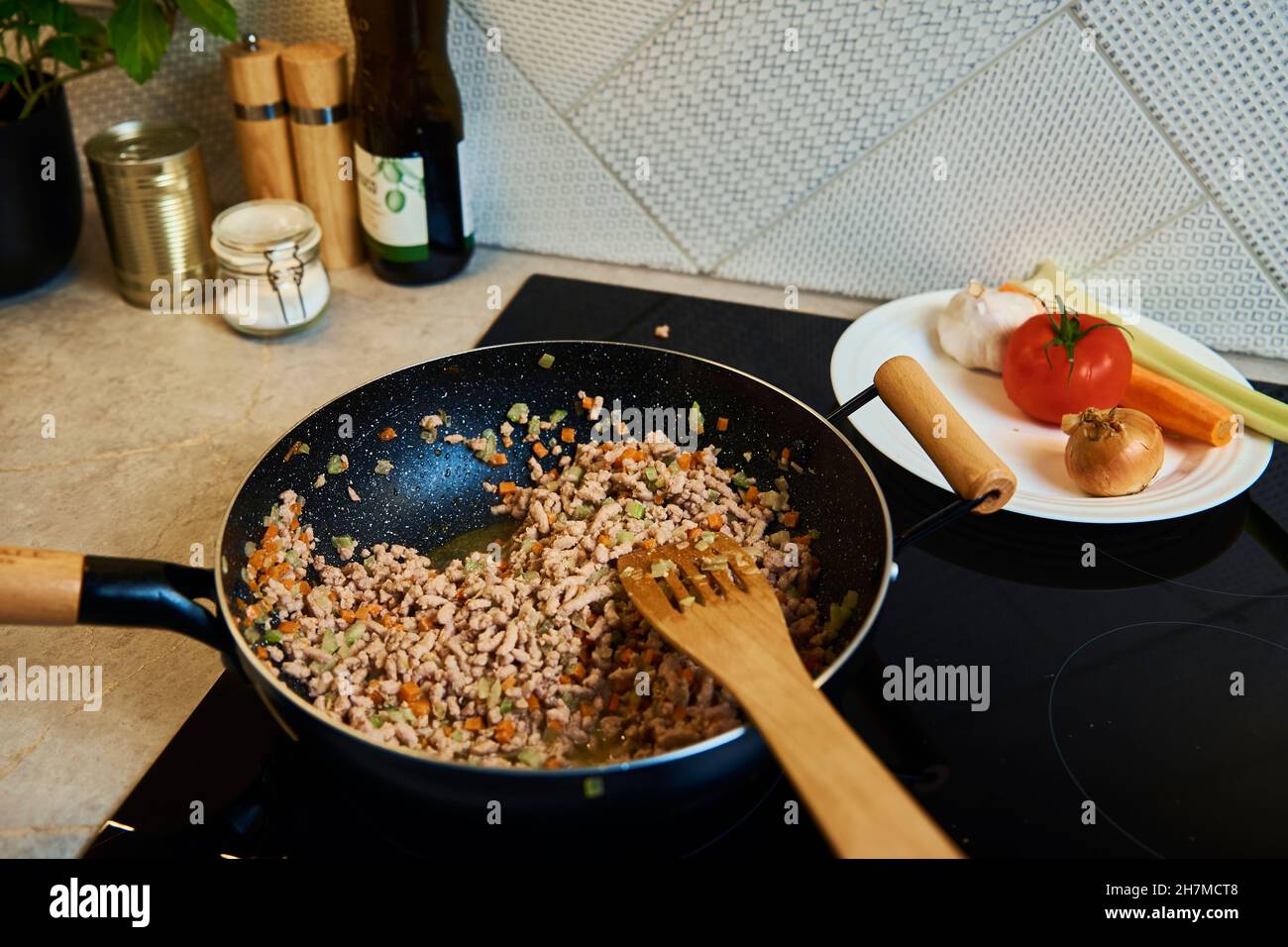 Nahaufnahme des Kochens von Bolognese-Sauce in der Pfanne auf Induktionsherd in der Küche Stockfoto