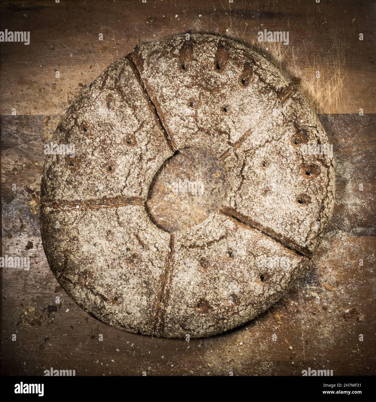 Rundes, flaches Roggenbrot mit einem Loch in der Mitte auf einem hölzernen Schnittbrett mit Semmelbröseln Stockfoto