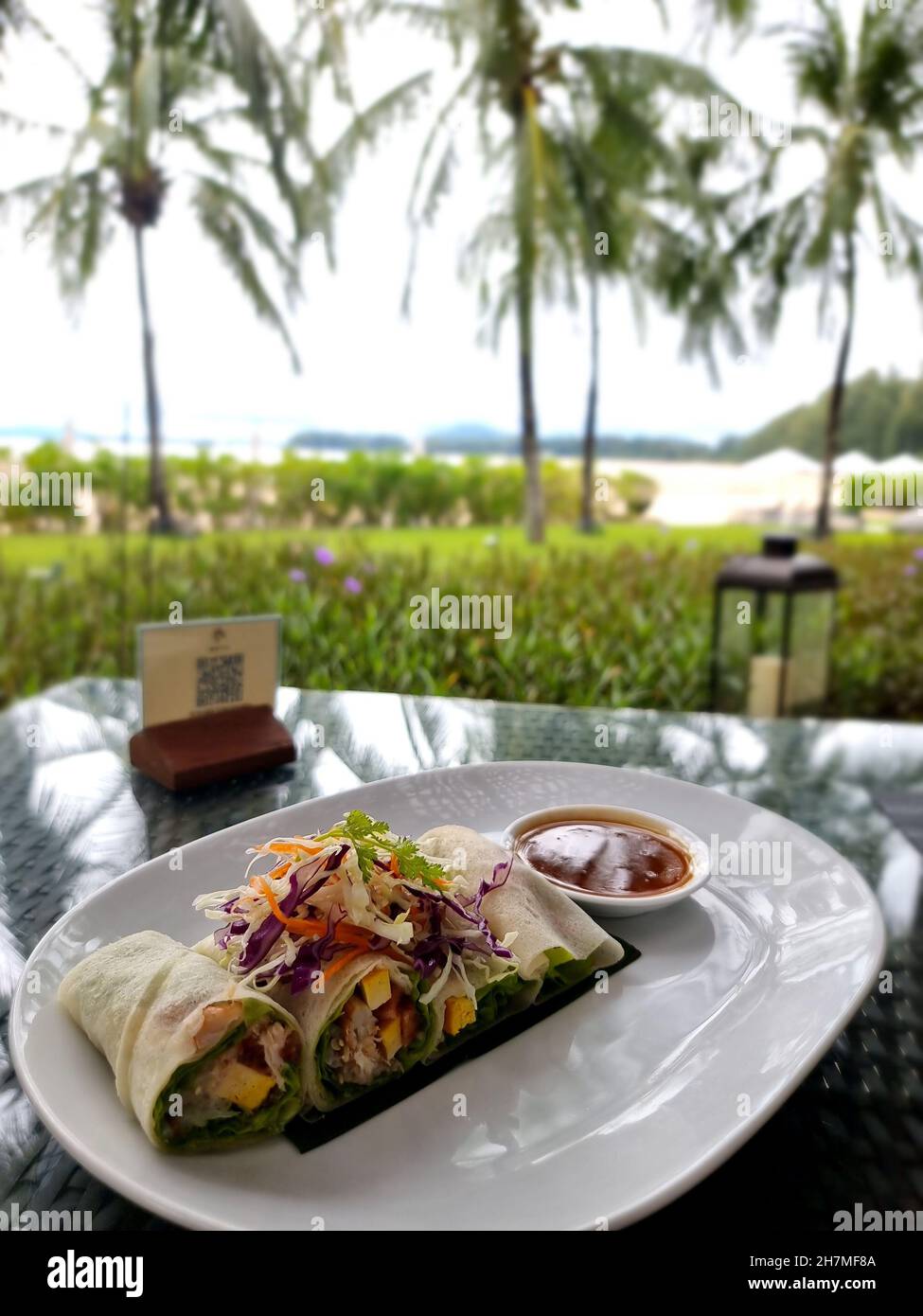 Teller zum Abendessen in einem Luxusrestaurant am Meer mit Fleisch und Salat. Thailändische Frühlingsrollen Stockfoto