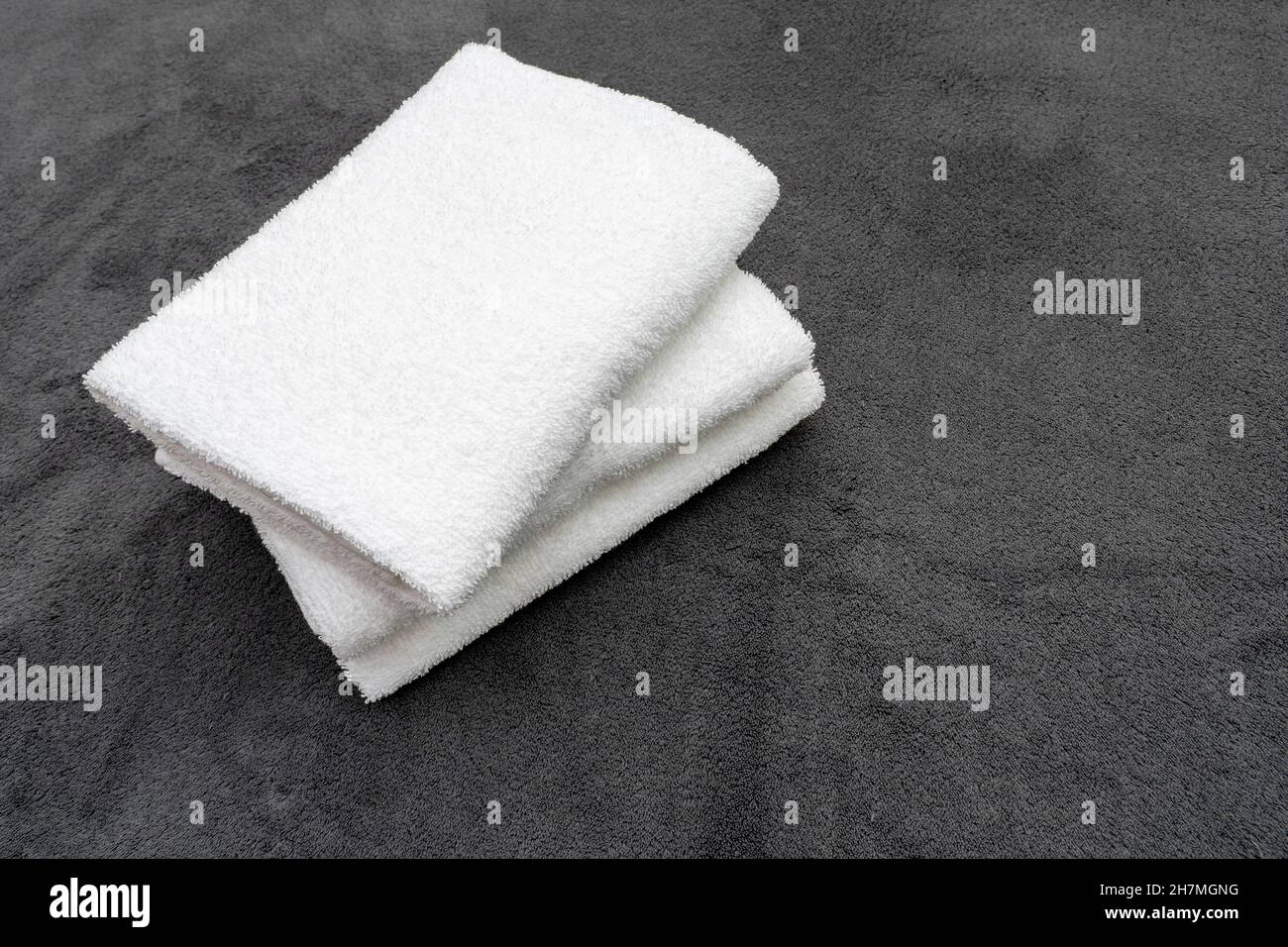 Drei weiße Handtücher auf dem grauen Plaid im Hotelzimmer Stockfoto