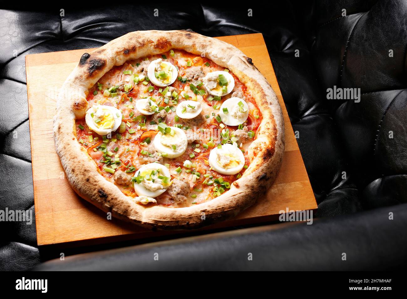 Pizza mit Speck, Ei und grünem Schnittlauch. Ein leckeres Gericht.kulinarische Fotografie. Vorschlag, das Gericht zu servieren. Stockfoto