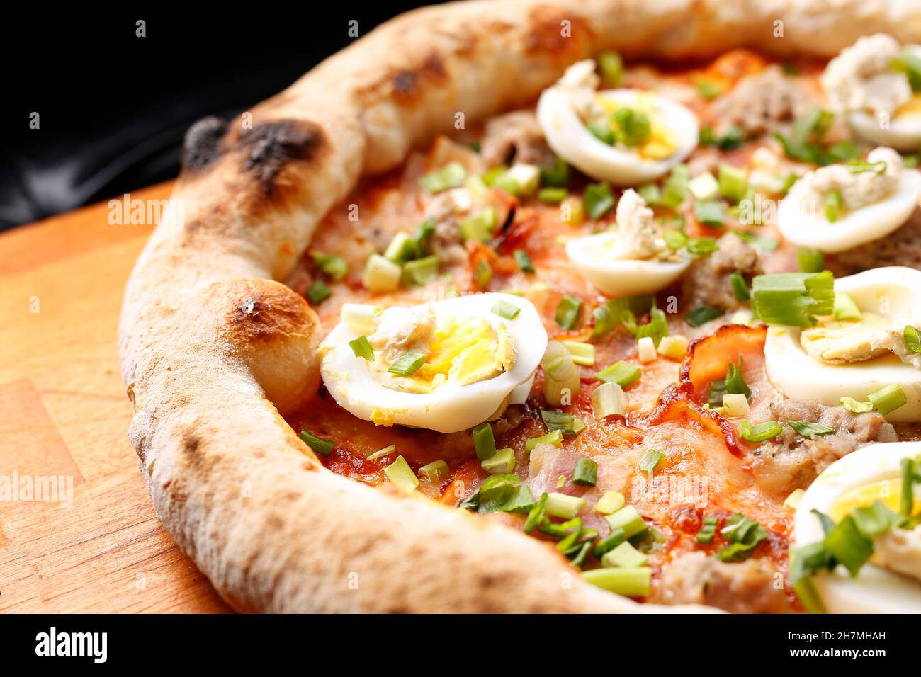 Pizza mit Speck, Ei und grünem Schnittlauch. Ein leckeres Gericht.kulinarische Fotografie. Vorschlag, das Gericht zu servieren. Stockfoto