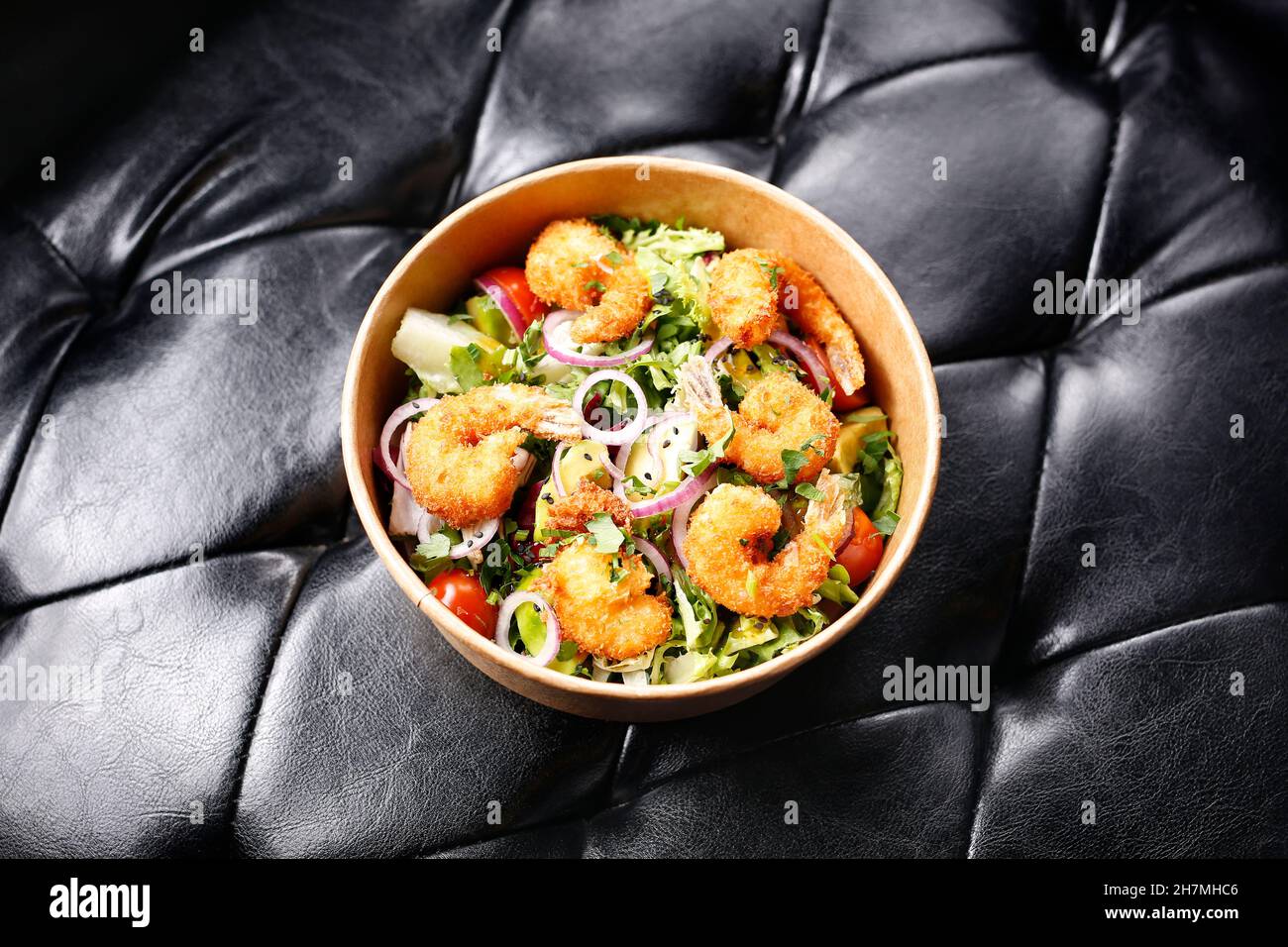 Gebratene Garnelen auf einem grünen Salat. Zum Mitnehmen, Diätbox. Appetitliches Fertiggericht in einer Einwegbox. Kulinarische Fotografie. Hintergrund der Speisen. Stockfoto