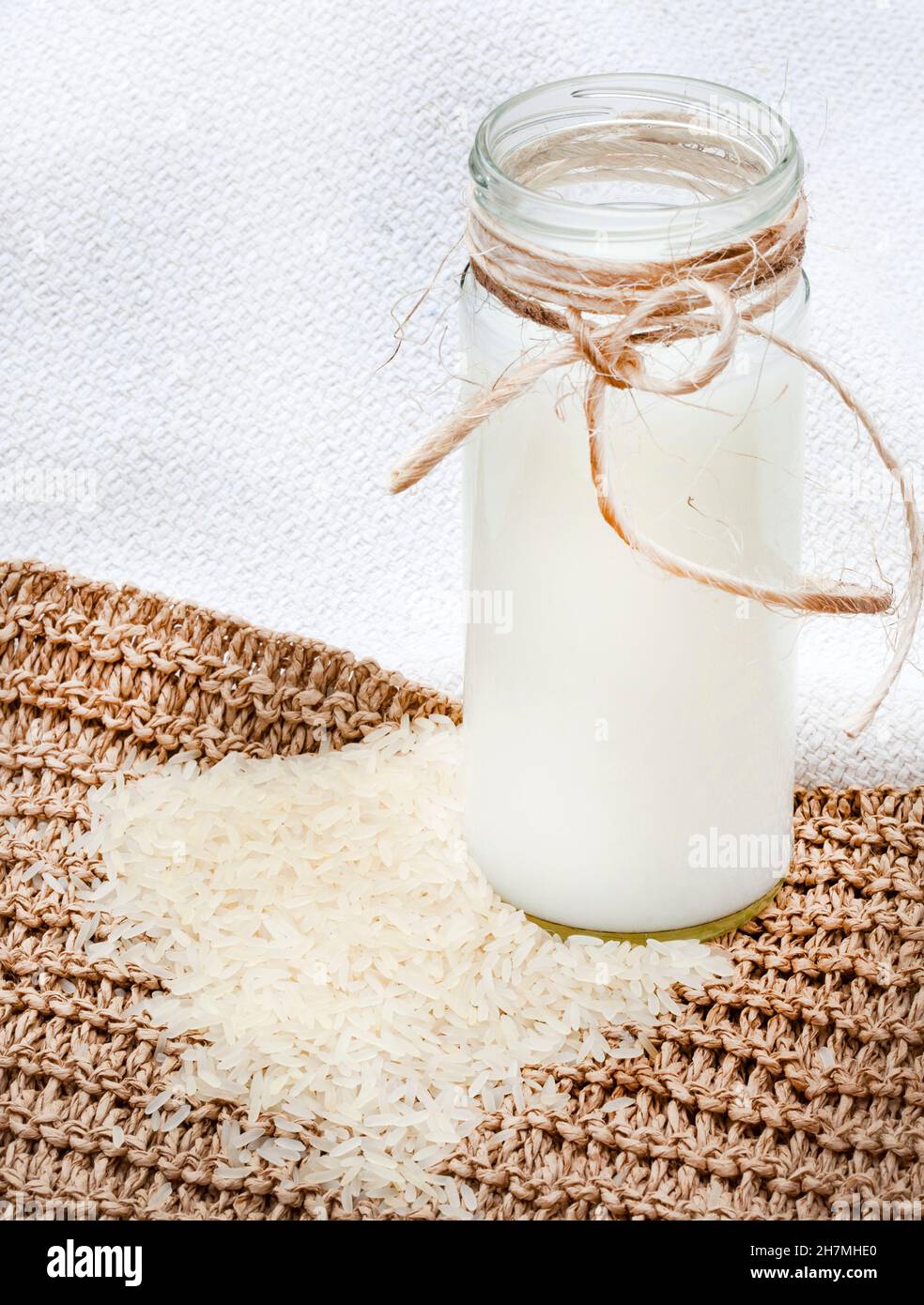 Rustikales Setting mit losem Reis um ein Glas Reismilch Stockfoto