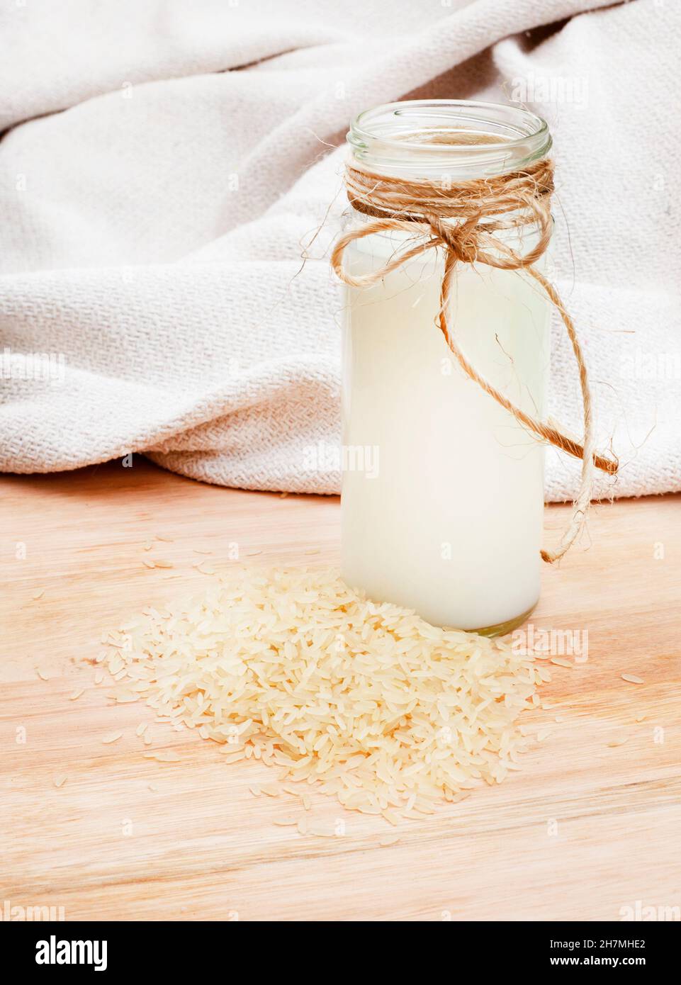 Rustikales Setting mit losem Reis um ein Glas Reismilch Stockfoto