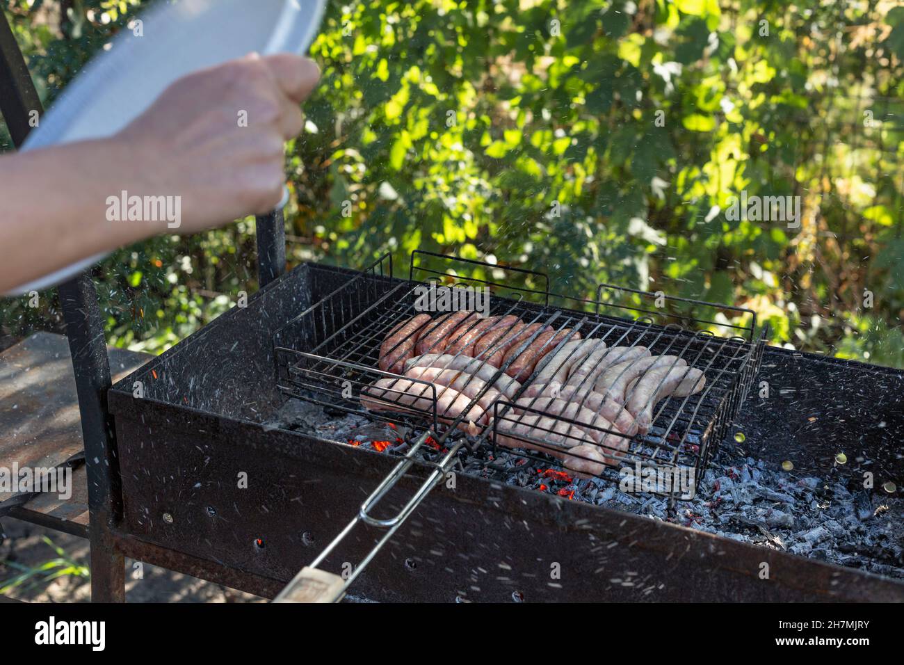 Frau Kochen Wurst am Grill Stockfoto