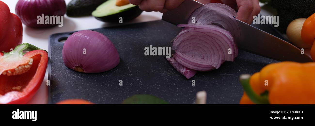 Koch schneidet rote Zwiebeln an Bord unter Gemüse aus der Nähe Stockfoto