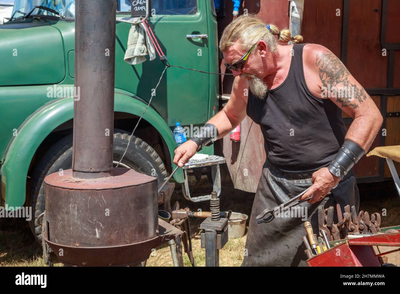 Ein Schmied, der draußen mit einer kleinen Schmiede auf einer Wandermesse arbeitet Stockfoto