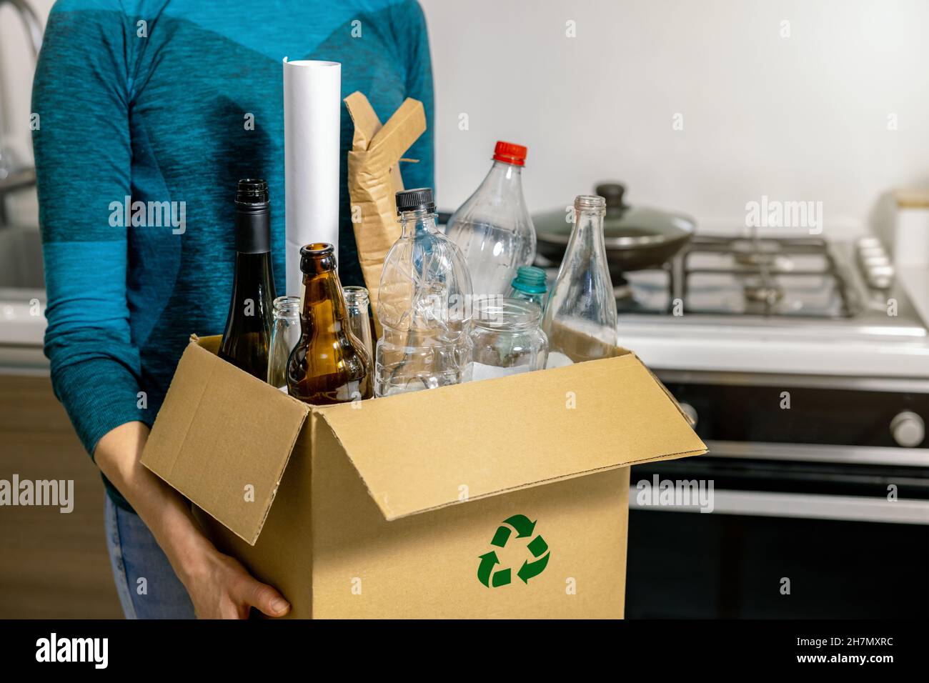 Sortierung und Recycling von Haushaltsabfällen - Frau hält einen Karton mit Plastik-, Glas- und Papiermüll Stockfoto