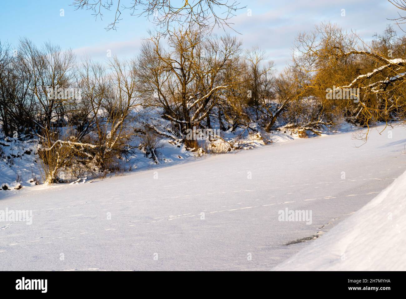 Ein Fluss, der an einem frostigen Wintertag komplett mit Eis bedeckt ist. Winter verschneite Landschaft. Horizontales Foto. Stockfoto