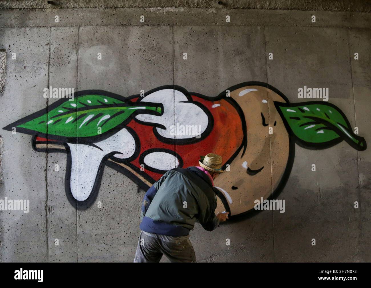 Der italienische Straßenkünstler Pier Paolo Spinazze, 39, bekannt als  'Cibo' (italienisch für Lebensmittel), verwendet Sprühfarbe, um rassistische  Graffiti mit einem Fototapete von Pizza zu bedecken, nahe Verona, Italien,  18. November 2021. Bild