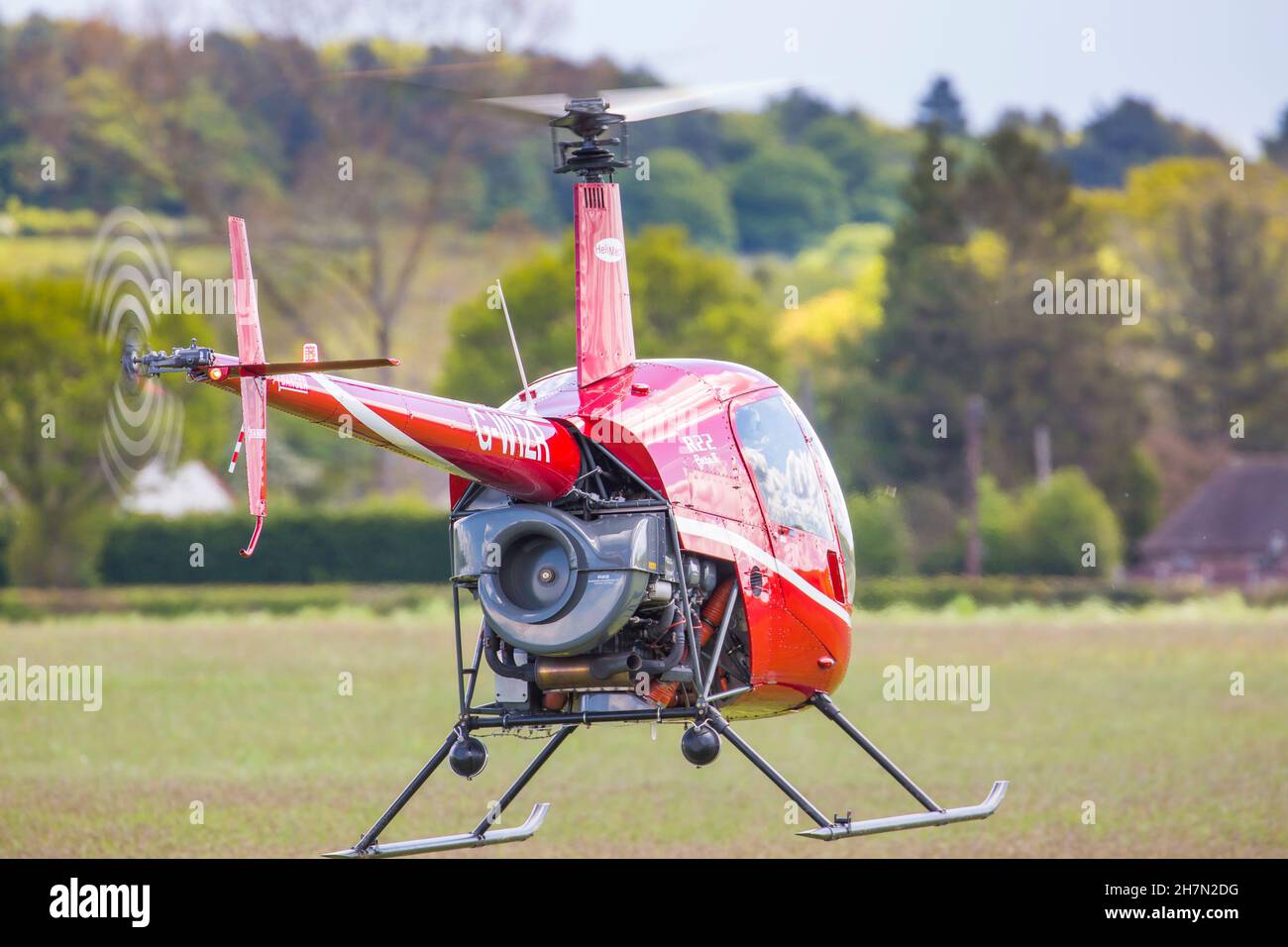 Nahaufnahme, Rückansicht eines kleinen, roten R22 Beta II-Hubschraubers, der vom Flugplatz Halfpenny Green, Großbritannien, vor Ort bekannt als Bobbington Airport, abfliegt. Stockfoto