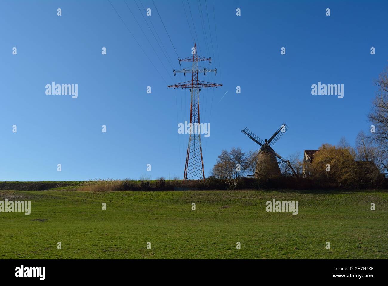 Traditionelle Windmühle und moderner Power Pole. Stockfoto
