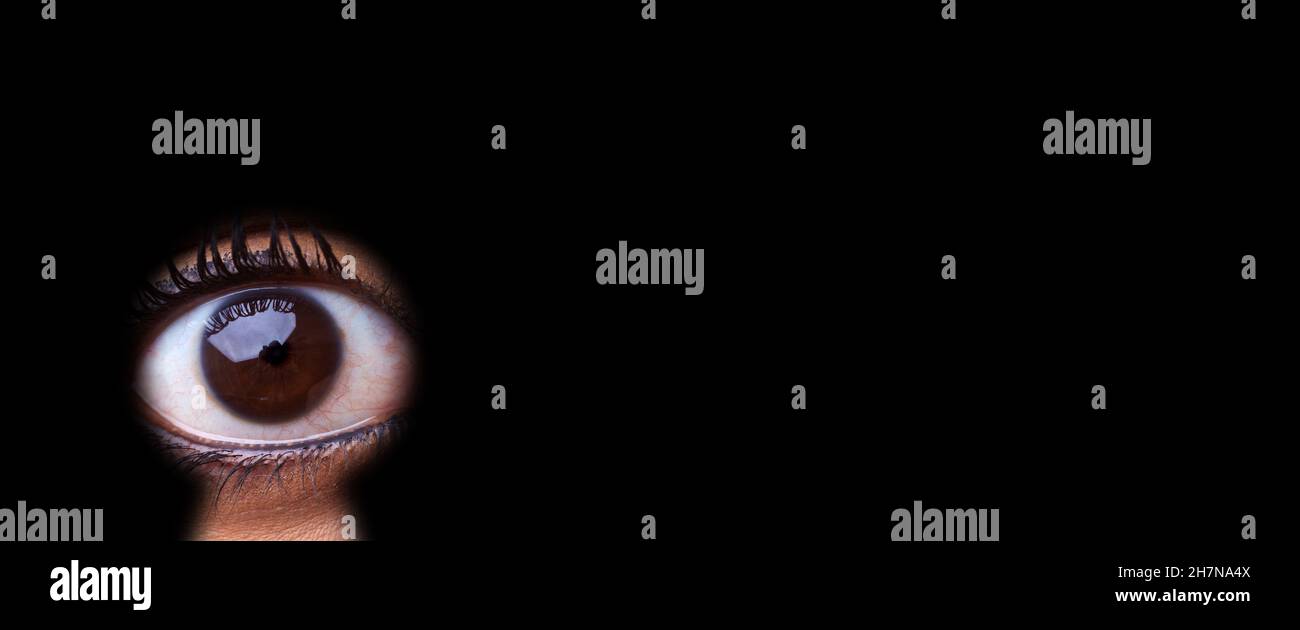 Weibliches Auge schaut als Spionin oder Privatdetektiv durch das Schlüsselloch Stockfoto