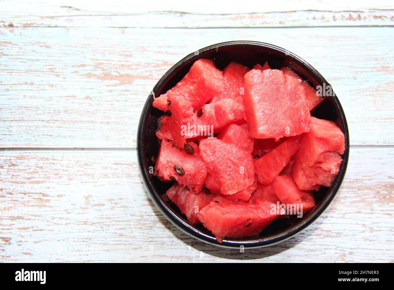 Gewürfelte Wassermelone in einer schwarzen Schale auf einem alten Holztisch. Blick von oben. Stockfoto