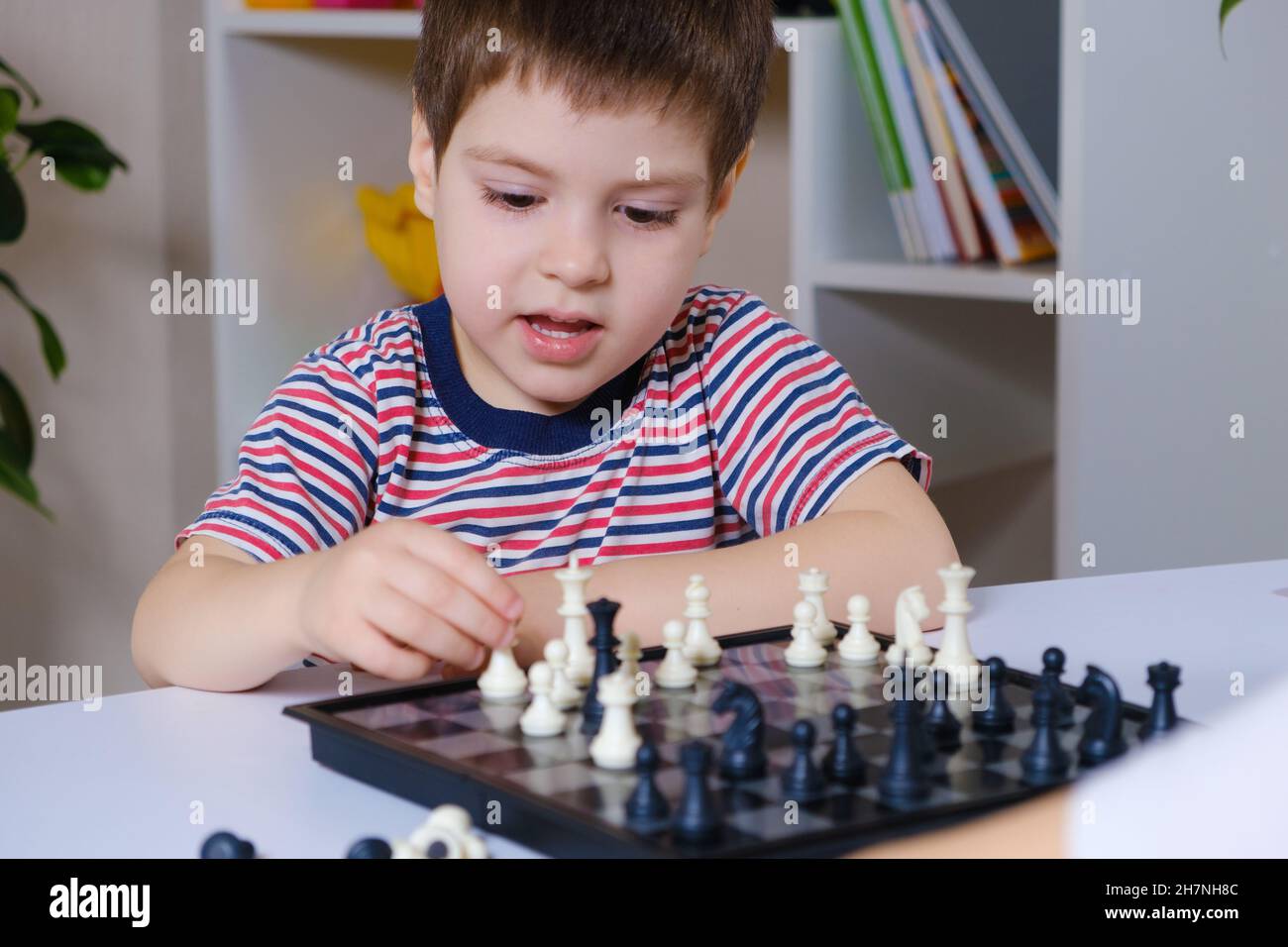 Ein Vorschuljunge spielt Schach, Brettspiele für Kinder. Stockfoto