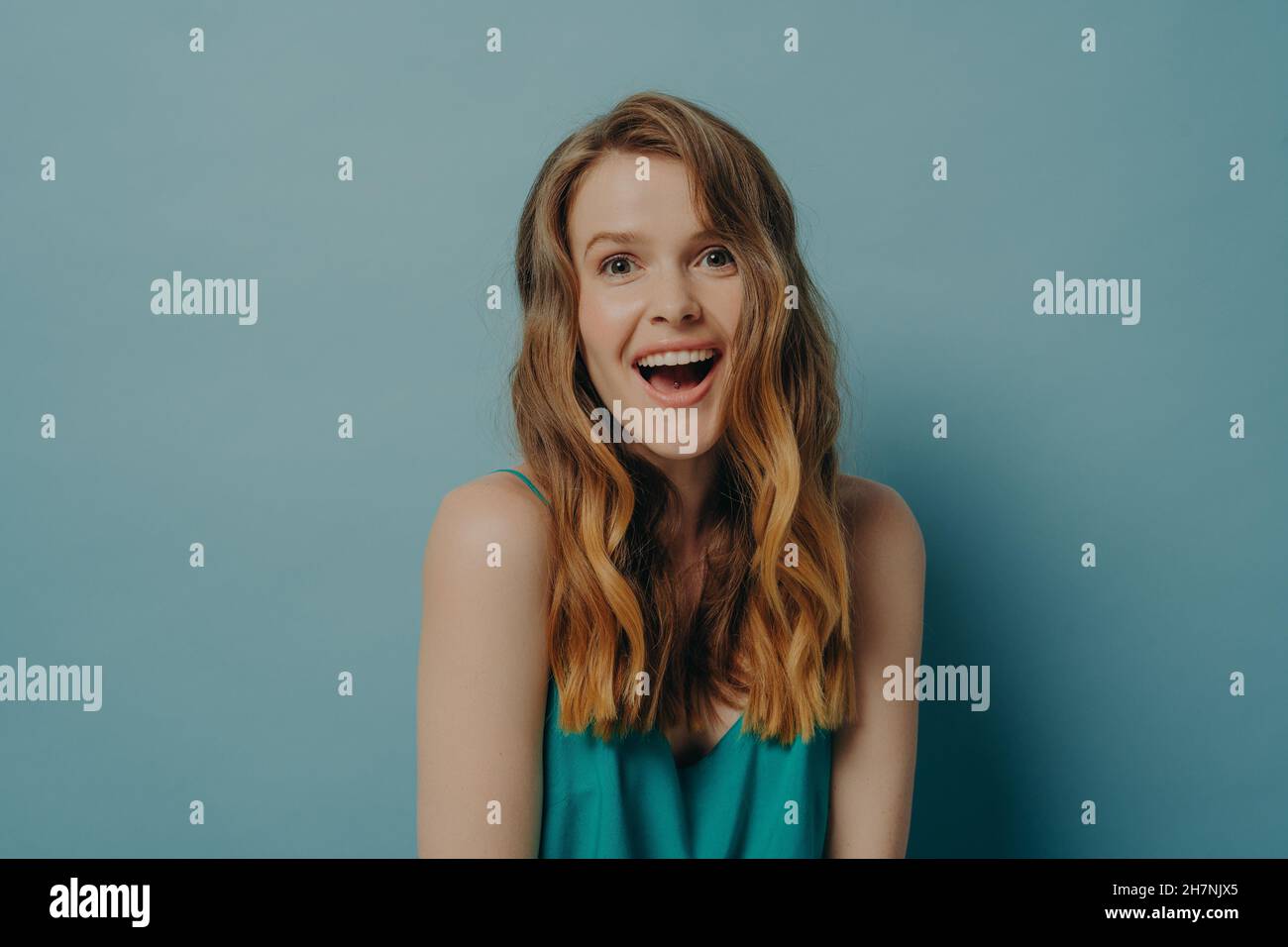 Aufgeregt junge Frau zeigt vor der Kamera positiv überrascht Gesichtsausdruck und breit toothy Lächeln Stockfoto