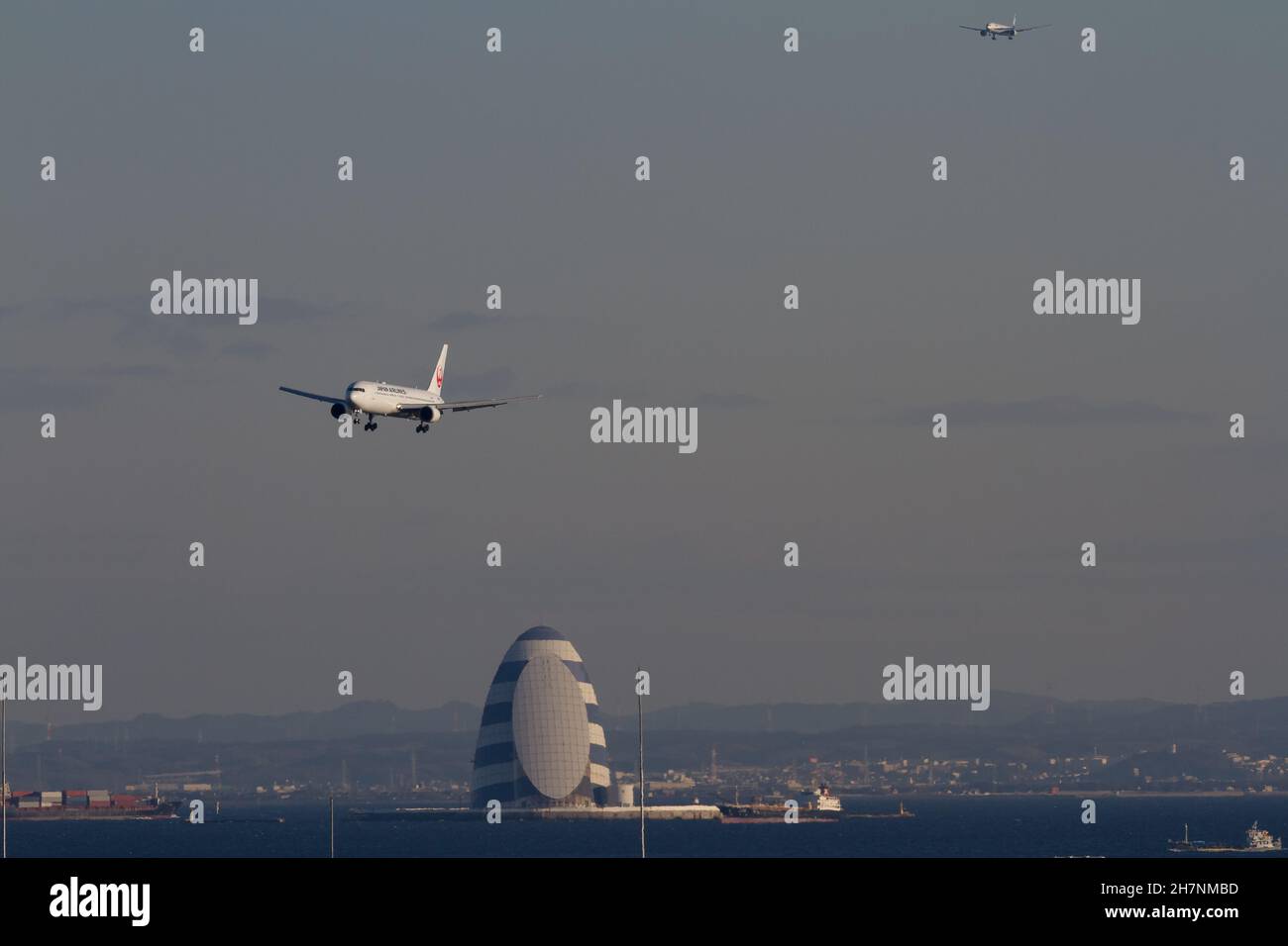 Die Passagierjets Japan Airlines (JAL) und All Nippon Airlines (ANA) landen am internationalen Flughafen Haneda über dem Tower of Wind in der Bucht von Tokio Stockfoto