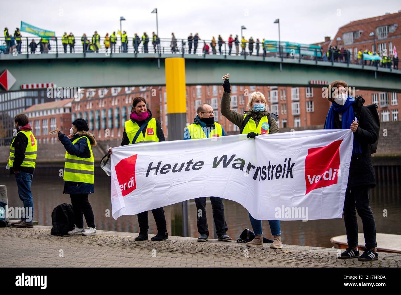 Bremen, Deutschland. 24th. November 2021. An der Weserpromenade zwischen Bürgermeister-Smidt-Brücke und Wilhelm-Kaisen-Brücke demonstrieren die Beschäftigten des öffentlichen Dienstes mit einer Menschenkette. Im anhaltenden Tarifkonflikt für die Beschäftigten der Bundesländer setzt die Gewerkschaft Verdi ihre Warnstreiks fort. Verdi und der Beamtenverband dbb fordern bundesweit fünf Prozent mehr Lohn für die mehr als eine Million Staatsangestellte, mindestens aber 150 Euro pro Monat und sogar 300 Euro mehr im Gesundheitswesen. Quelle: Sina Schuldt/dpa/Alamy Live News Stockfoto