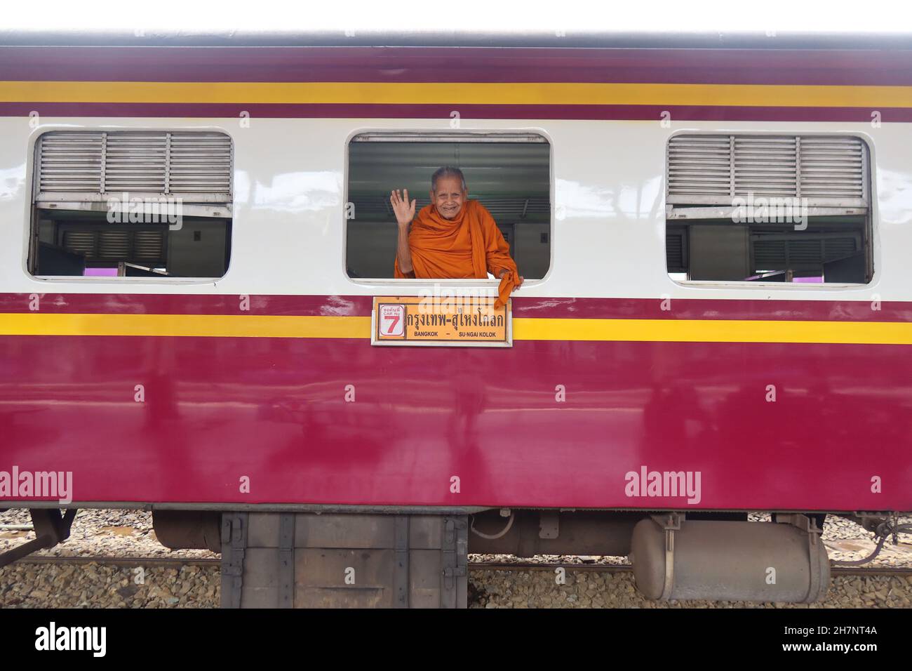 Lächelnder Mönch winkt vom Zug am Bahnhof Bangkok, Thailand Stockfoto