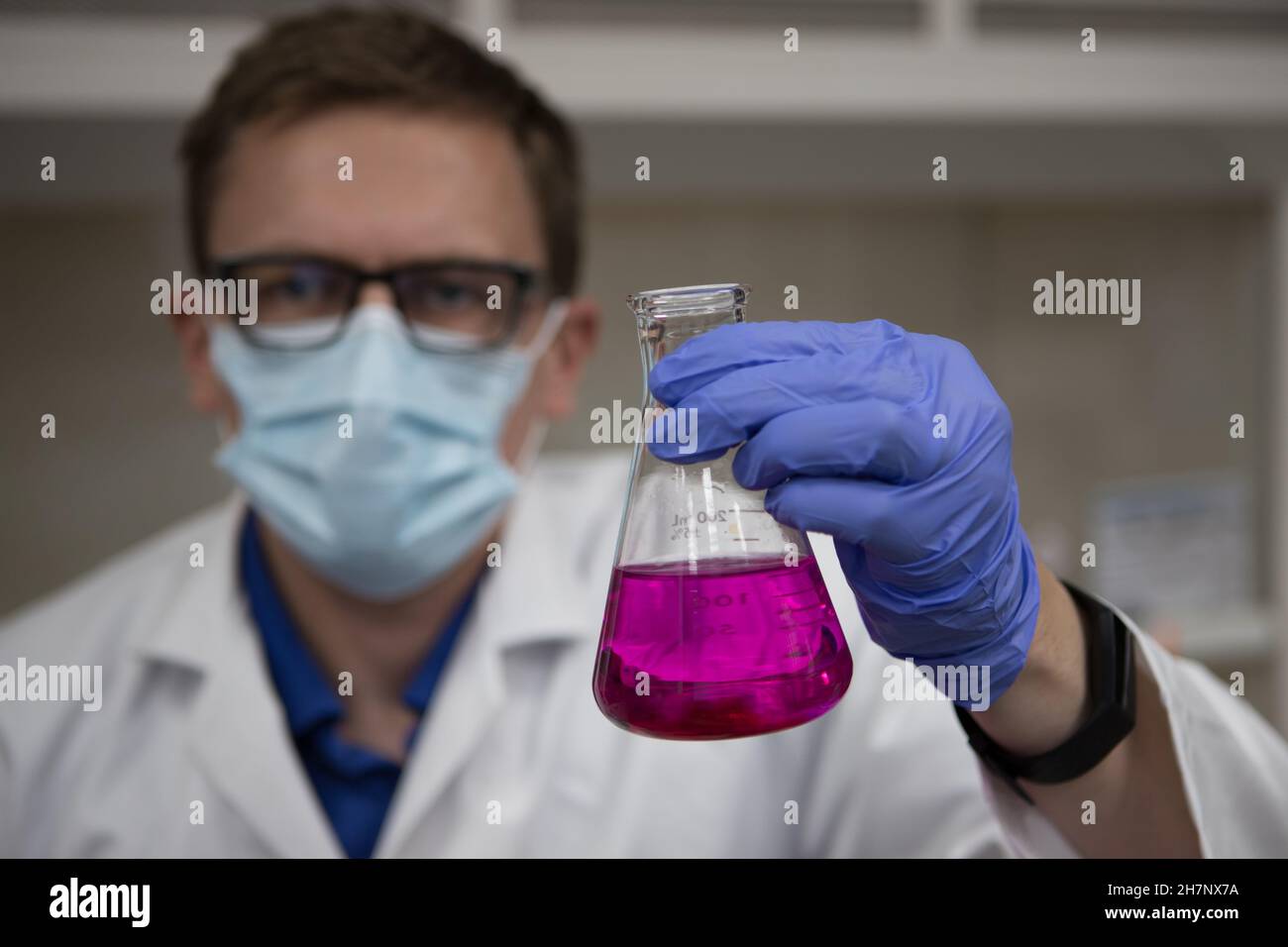 Wissenschaftler in einem Labor, das einen Messkolben mit einer violetten Chemikalie hält. Titrationsanalyse Stockfoto