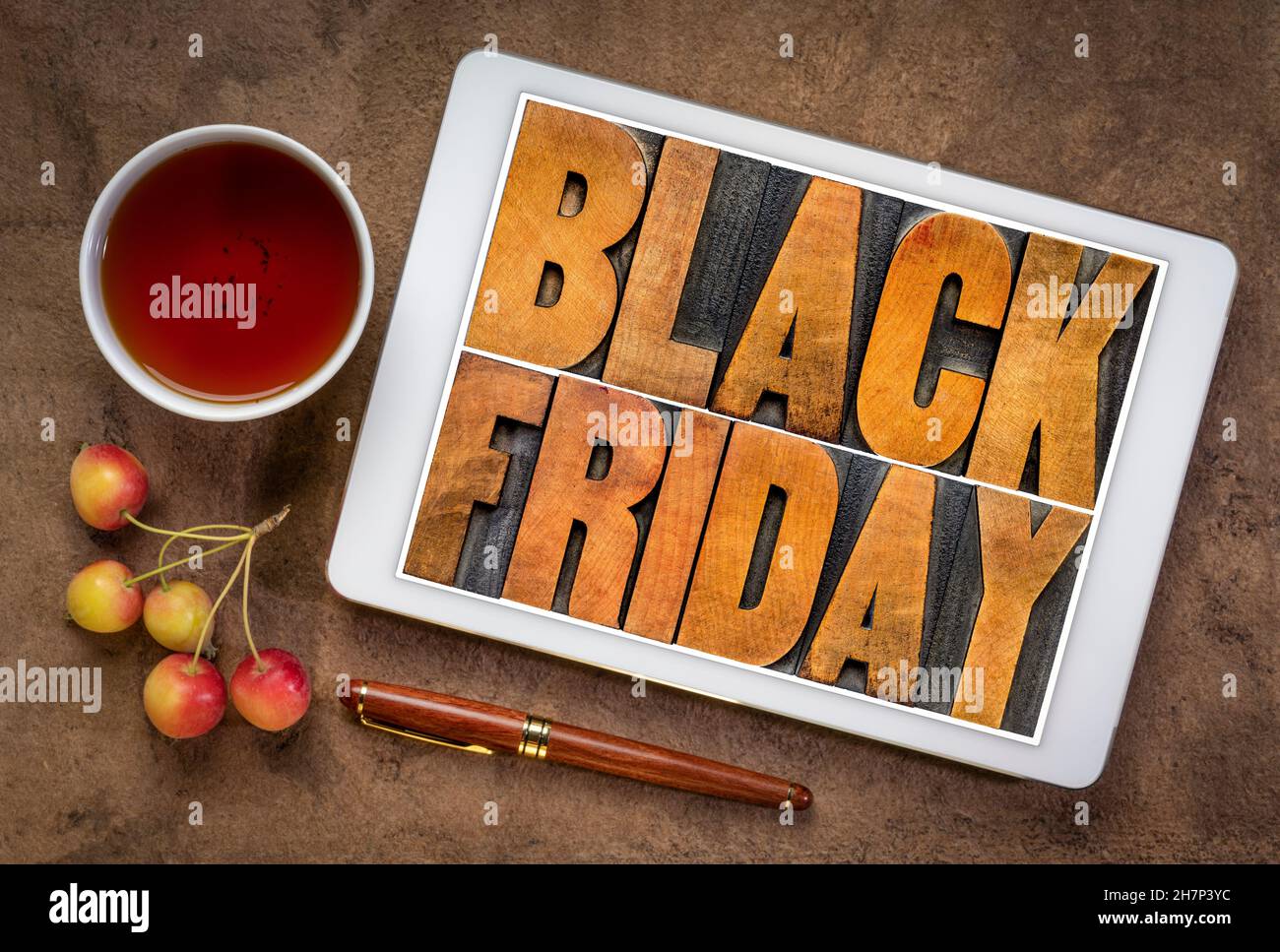 Black Friday - Holiday Shopping Concept - Wortabstrakt im Vintage-Buchdruck Holzart auf einem digitalen Tablet mit einer Tasse Tee und Krabbenäpfeln Stockfoto