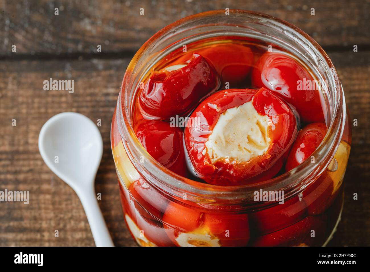 Gefüllte Kirschpaprika mit Ricotta-Käsefüllung im Glas auf Holzboden Stockfoto