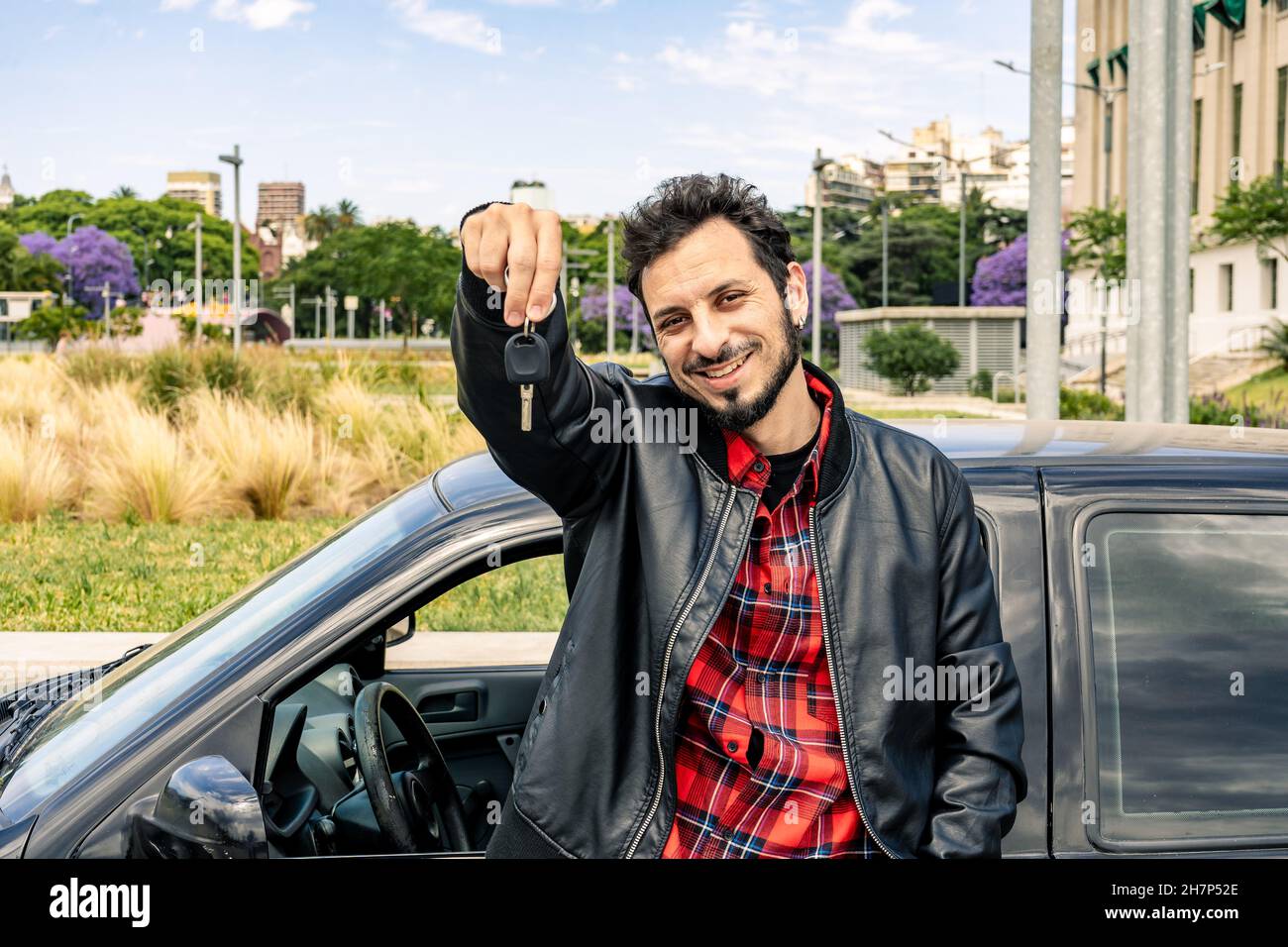 Ein glücklicher junger mann aus lateinamerika zeigt die Schlüssel seines neuen Autos. Konzept von Mobilität, Transport, Verbesserung. Stockfoto