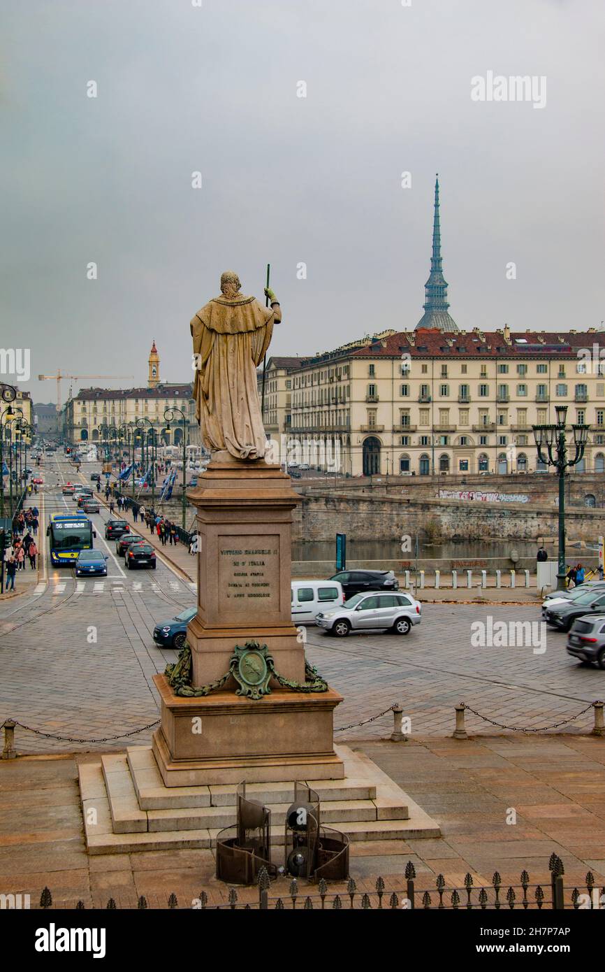 Statue eines Königs Vittorio Emanuele I, der vorwärts geht, einen Stab in seinem rechten Arm hält und der Ponte Vittorio Emanuele I über dem Fluss Po, Turin, gegenübersteht Stockfoto