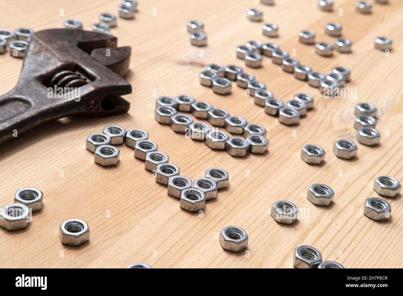 Die Nummer 2022 ist auf einem Holztisch neben einem großen, alten Schraubenschlüssel mit Metallmuttern ausgekleidet. Konzept der Vorbereitung auf das neue Jahr. Stockfoto