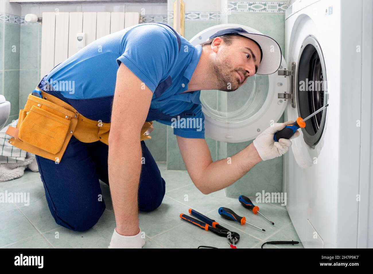 Ein fachkundiger Mechaniker repariert eine defekte Waschmaschine Stockfoto