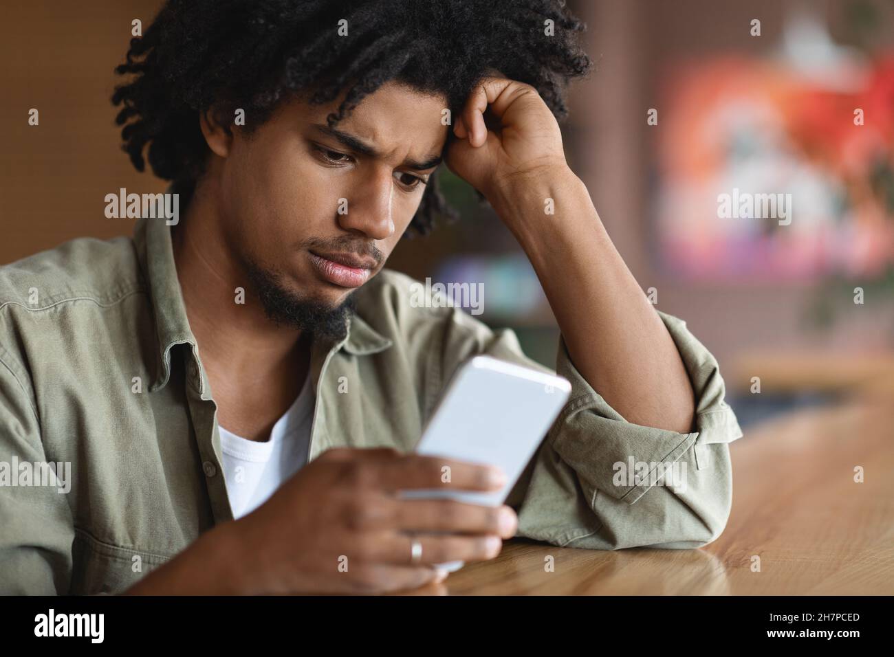 Schlechte Nachrichten. Verärgert Schwarz Kerl Blick Auf Smartphone, Während Sitzen Im Café Stockfoto