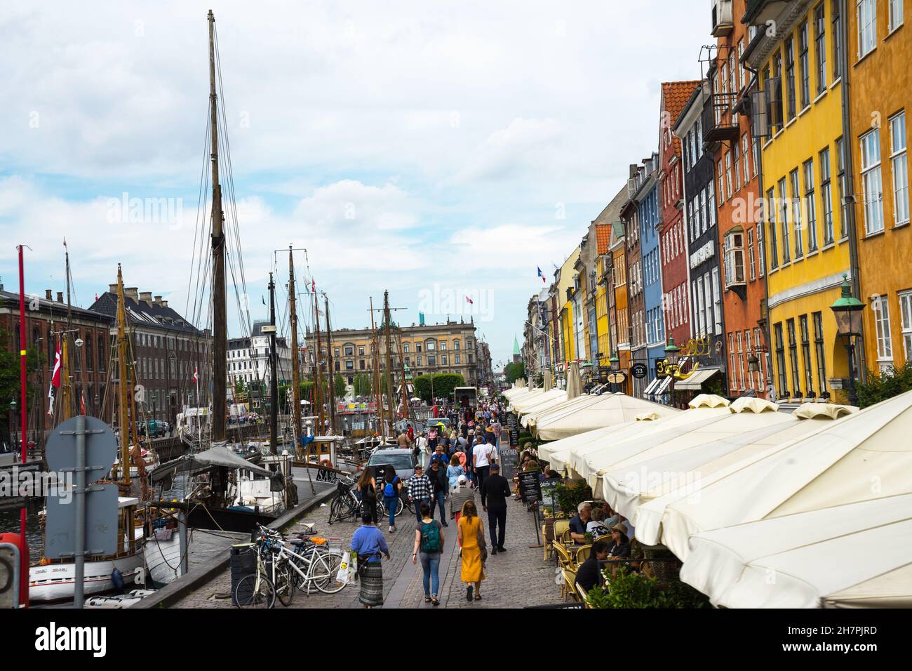 Nyhavn ist eine Uferpromenade und ein Kanal in Kopenhagen, Dänemark. Spaziergänger, bunte Häuserfassaden und alte Schiffe entlang des Kanals. Holzschiffe moore Stockfoto