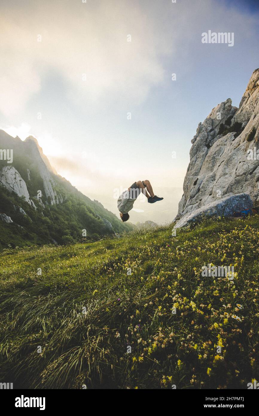 Junger Mann, der auf einem Berg in der Luft springt Stockfoto