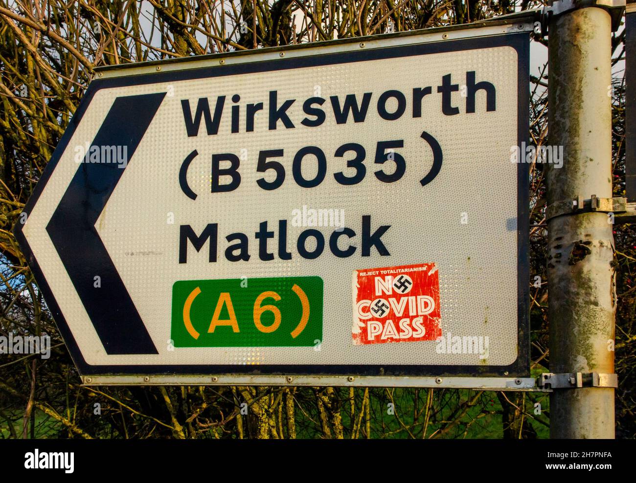 Kein Covid Pass-Aufkleber mit Hakenkreuz auf einem Straßenschild in der Nähe von Matlock im Derbyshire Peak District England Großbritannien während der Coronavirus-Pandemie von 2021. Stockfoto