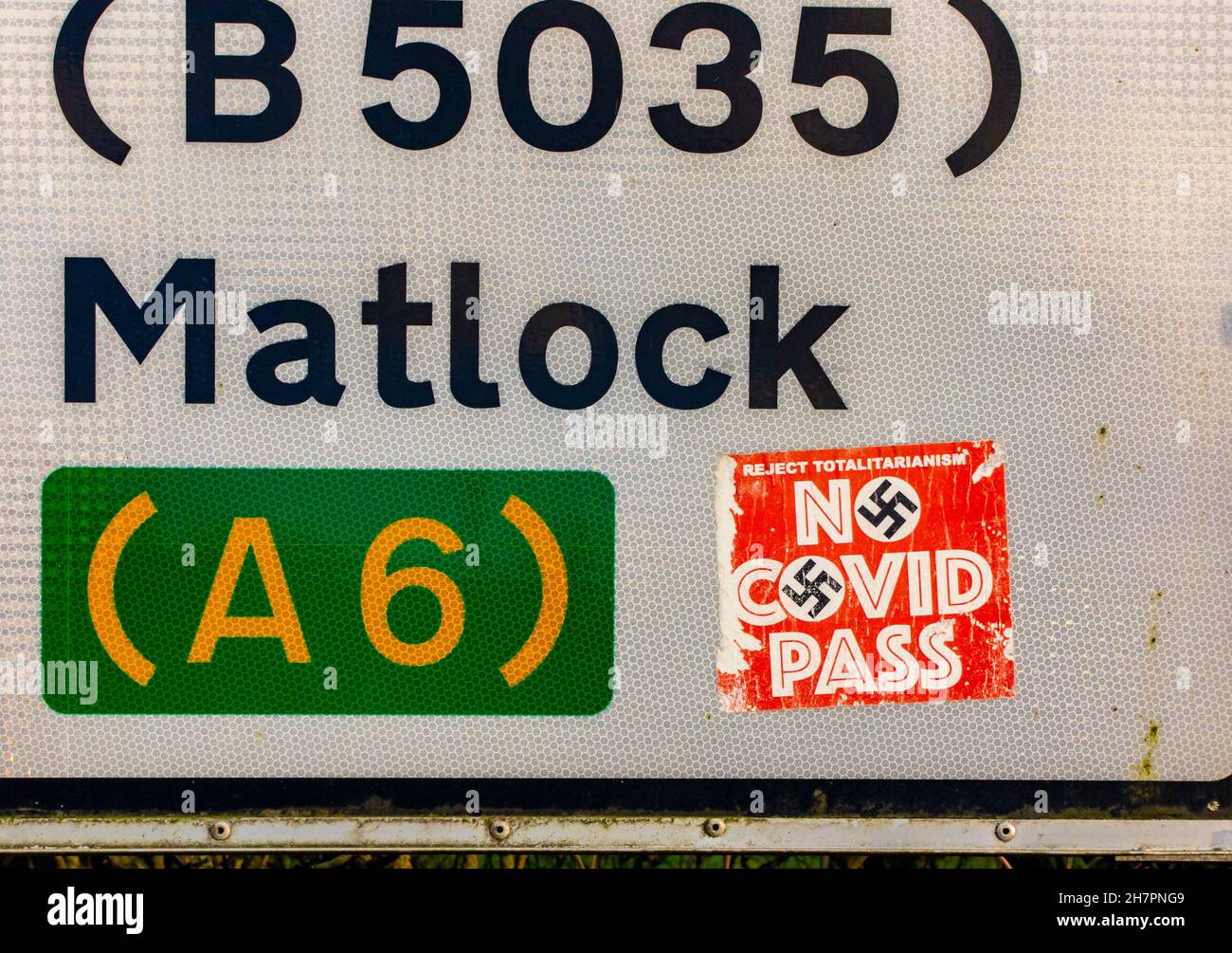 Kein Covid Pass-Aufkleber mit Hakenkreuz auf einem Straßenschild in der Nähe von Matlock im Derbyshire Peak District England Großbritannien während der Coronavirus-Pandemie von 2021. Stockfoto
