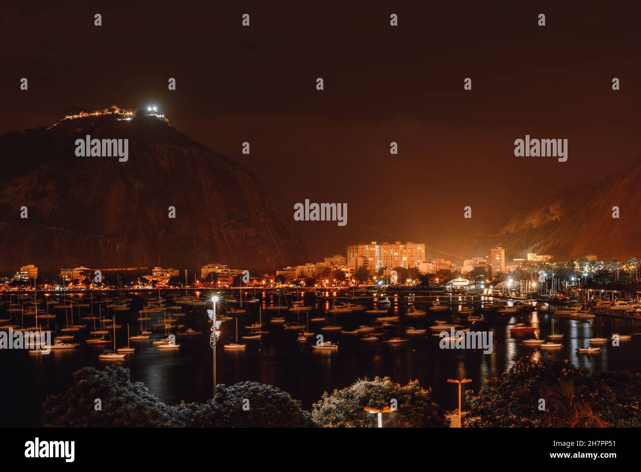 Eine Nachtaufnahme einer Bucht von Botafogo in Rio de Janeiro, Brasilien, mit vielen Segelbooten, die leicht auf dem Wasser schwanken, einem Berg Stockfoto