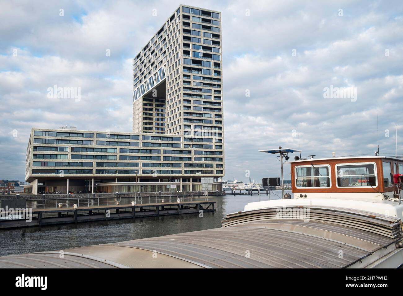 Pontsteiger Appartementhaus im westlichen Hafengebiet von Amsterdam mit umgebauter Barge im Vordergrund. Stockfoto