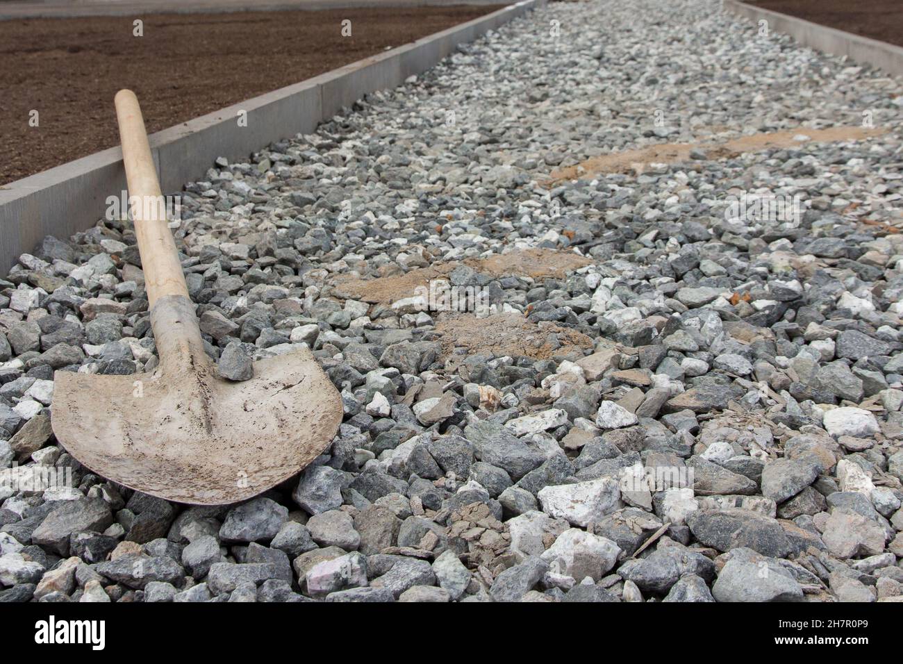 Bauschaufel auf einem mit Schutt gesäumten Pfad. Bauwerkzeug. Stockfoto
