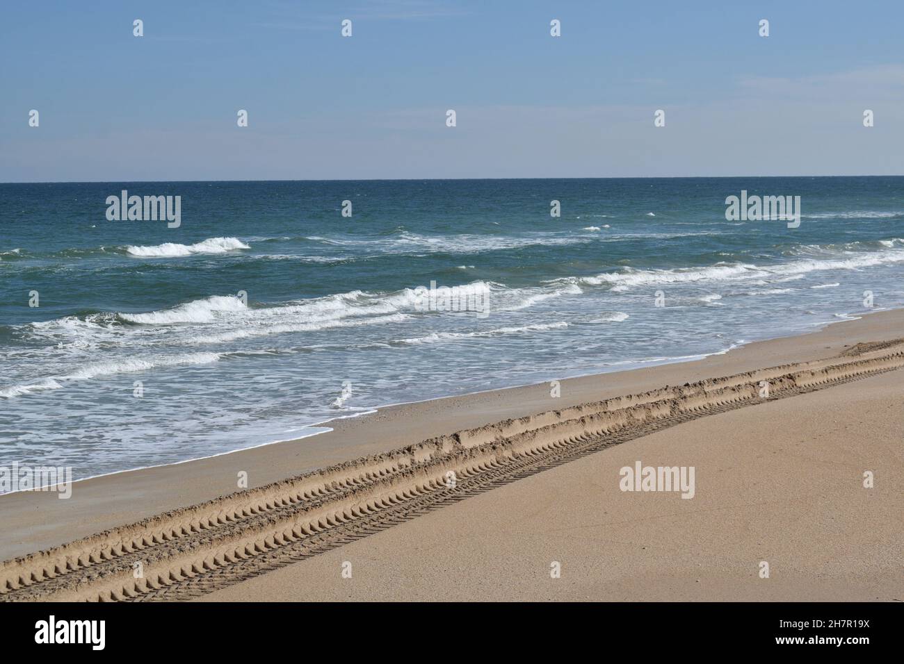 Im weichen Sand am Strand sind tiefe Reifenspuren zu erkennen. Stockfoto