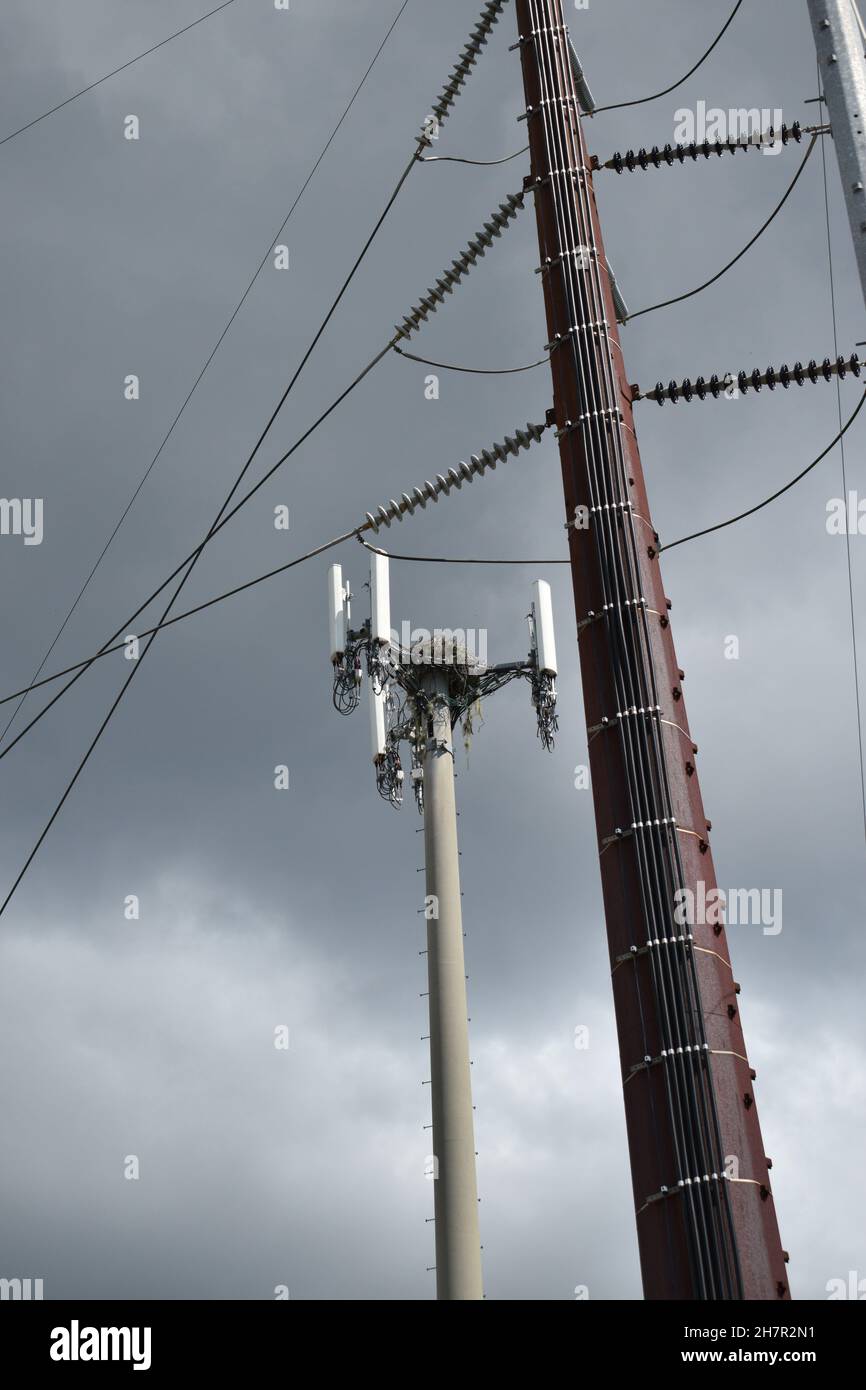 Ein kleinerer Turm steht im Kontrast zu einem superhohen Zellenturm. Stockfoto