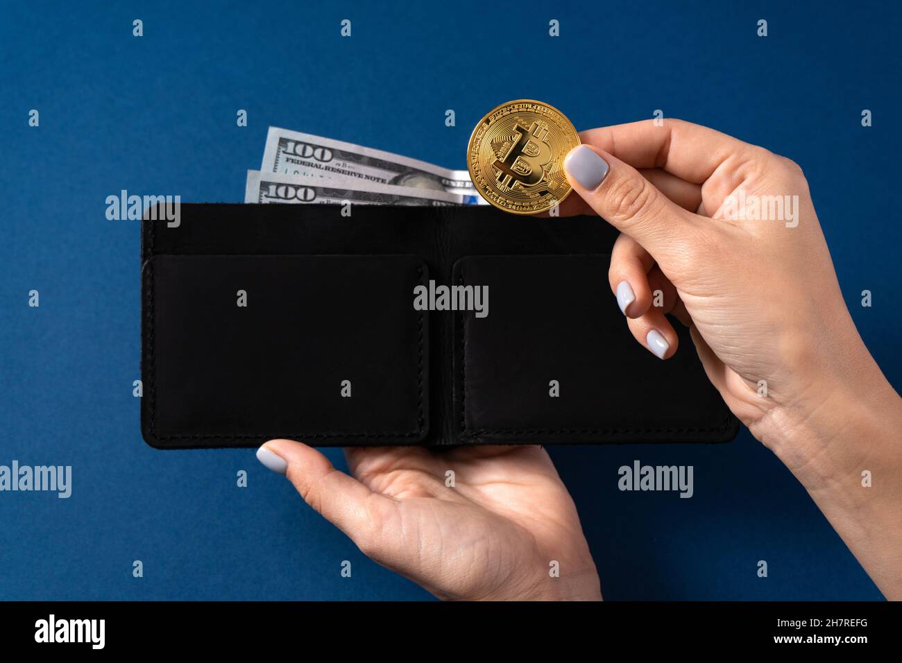 Goldbitcoin und 100-Dollar-Scheine in einer Ledertasche, die von einem Mädchen gehalten wird. Bitcoin mit Dollar in der Brieftasche. Bergmann mit Dollar und Goldbitcoins. Bus Stockfoto