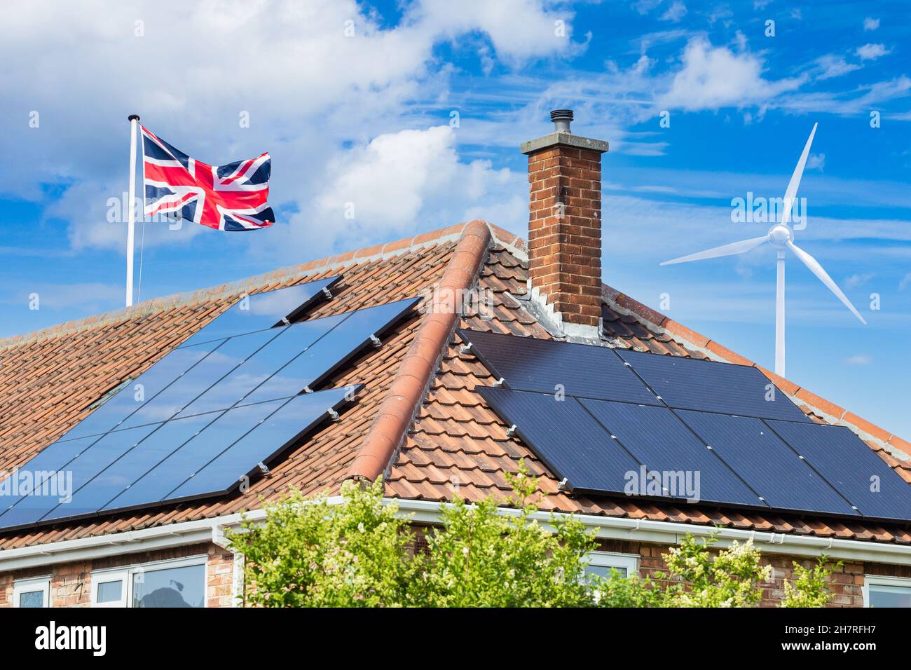 Solarmodule auf dem Hausdach in Großbritannien mit Windturbine. Solare, erneuerbare, grüne, saubere, alternative Energie. Haus, Haushalt Stromrechnungen ... Konzept Stockfoto