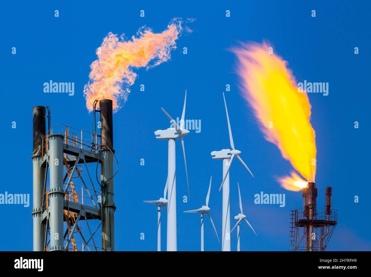 Gasflackern von Chemieanlagen und Koksofen mit Windenergieanlagen. Fossile Brennstoffe, Klimawandel, globale Erwärmung, erneuerbare Energien, Luftverschmutzung... Konzept Stockfoto
