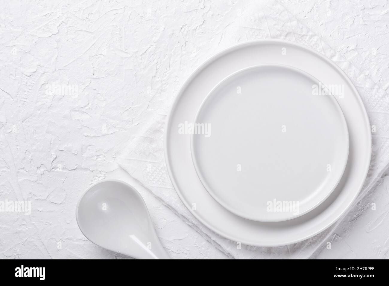 Weißer leerer Teller mit Löffel auf weißem Hintergrund Stockfoto