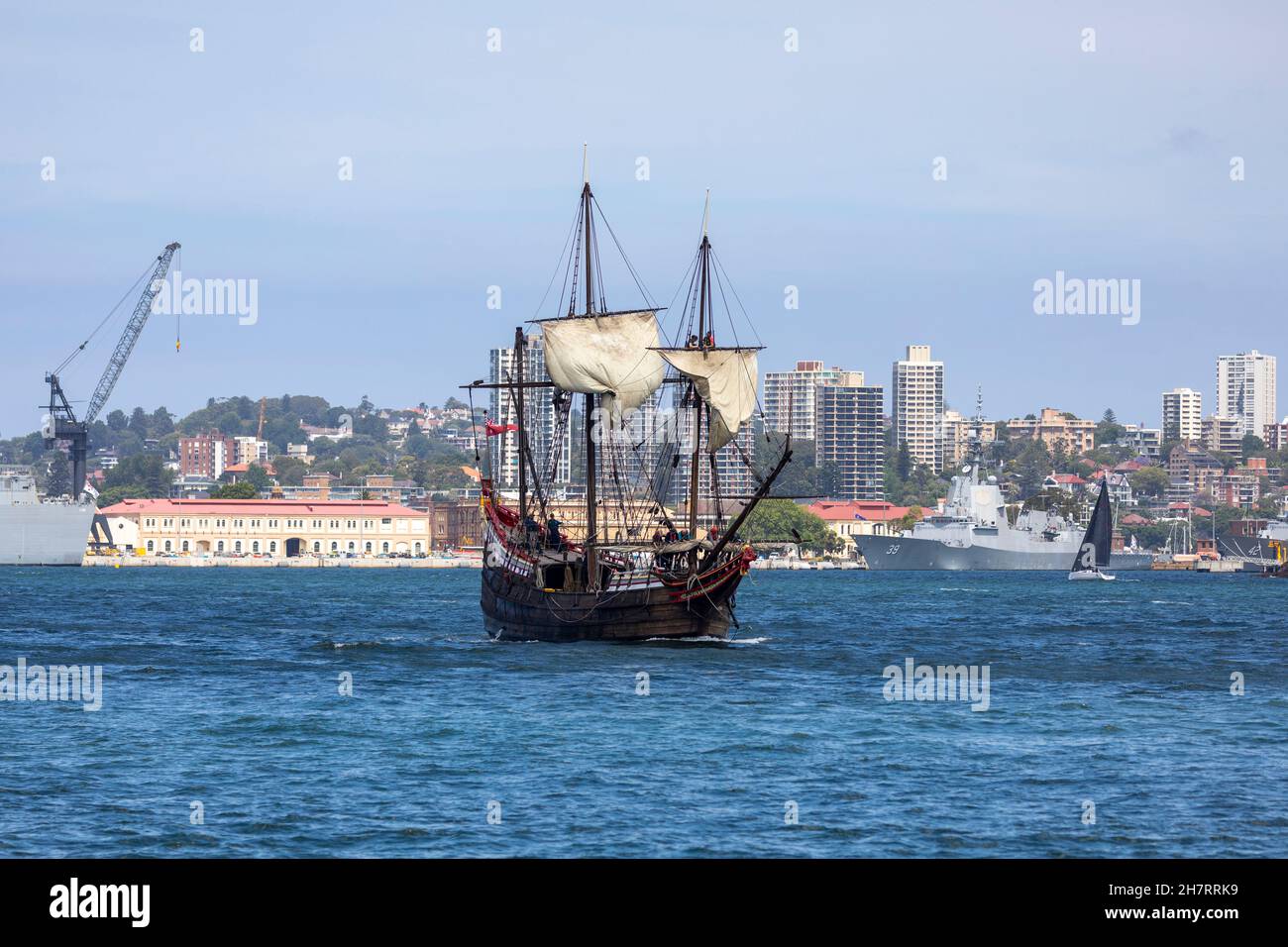 Traditionelles Segelboot im Hafen von Sydney, das an den australischen Marineschiffen vorbeifährt, die auf Garden Island, im Stadtzentrum von Sydney, NSW, Australien festgemacht sind Stockfoto