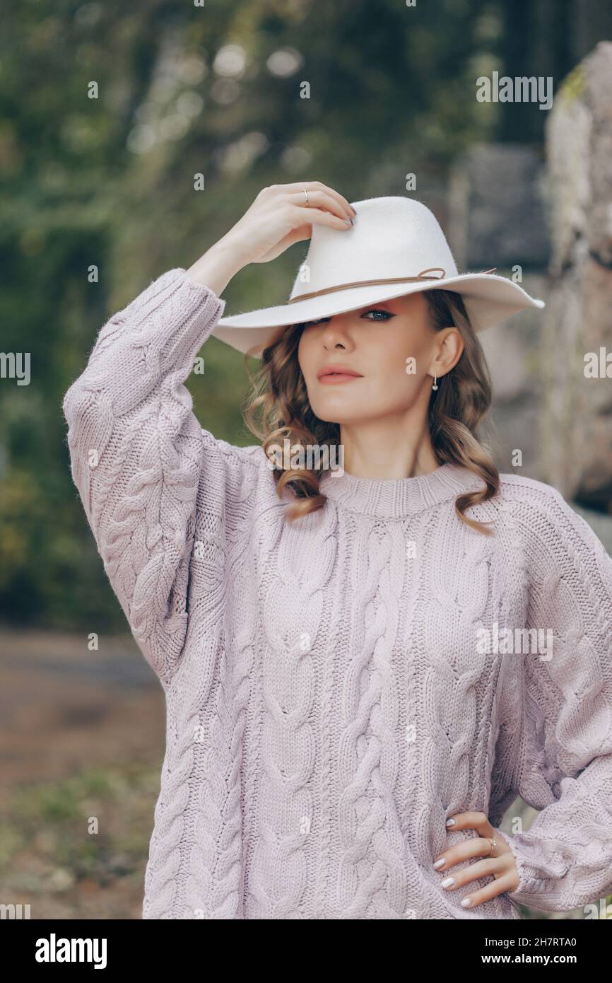 Blondine in einem weißen Hut geht an einem Herbsttag im Park Stockfoto